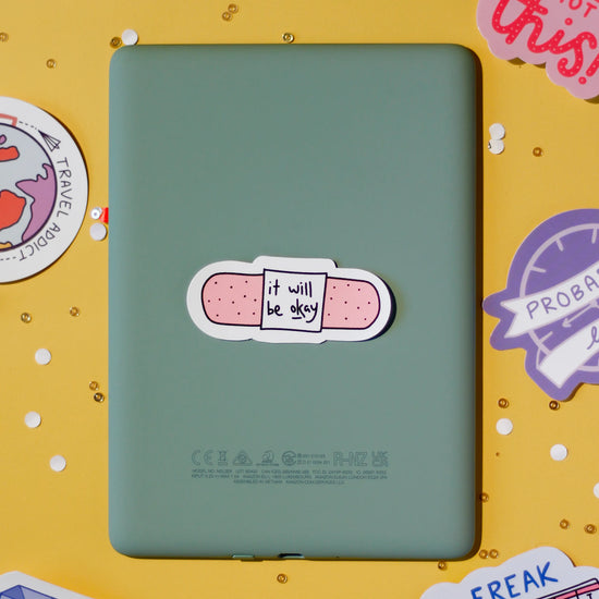 A cute bandage sticker saying 'it will be okay' on a yellow background.