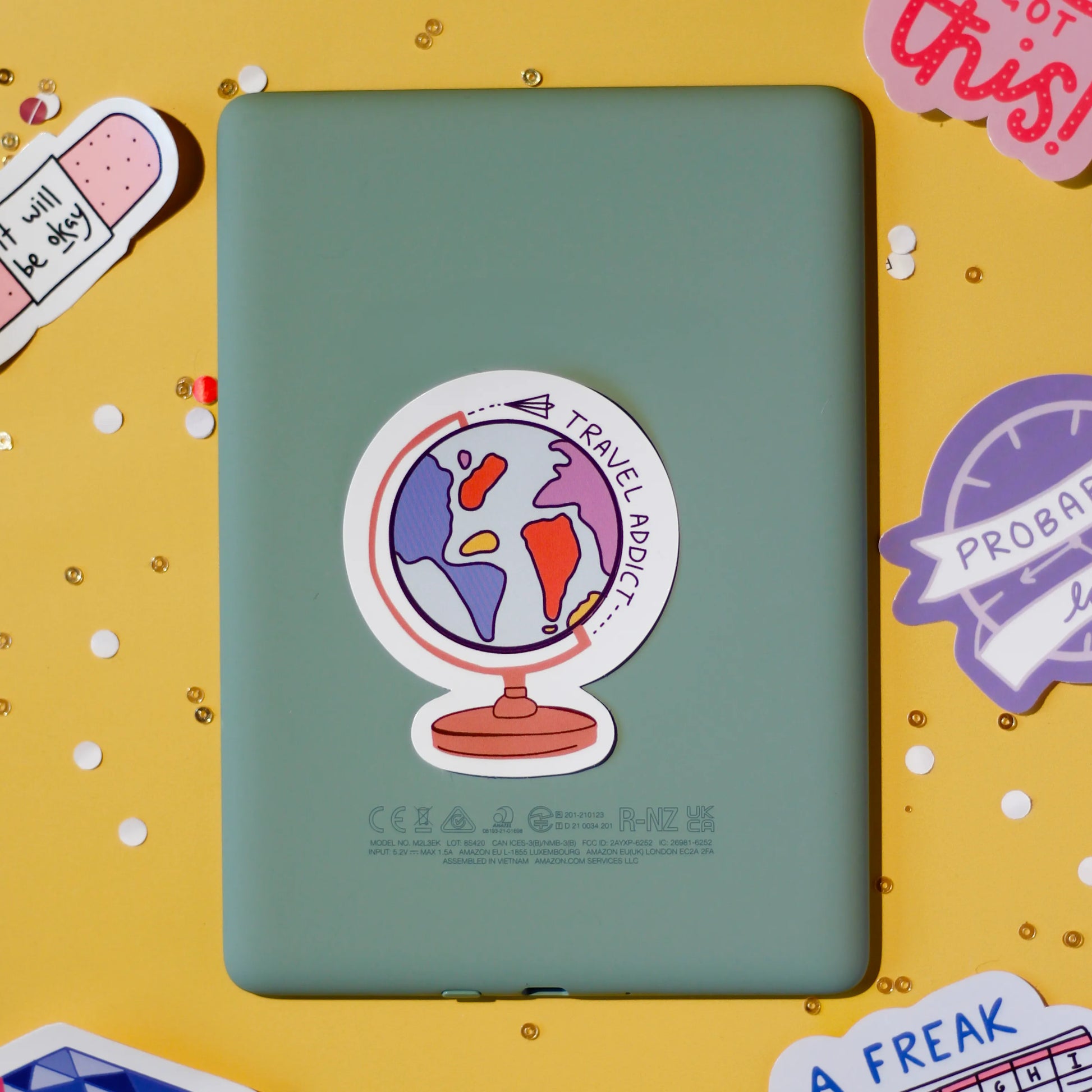 A 'Travel Addict' sticker on a yellow background.