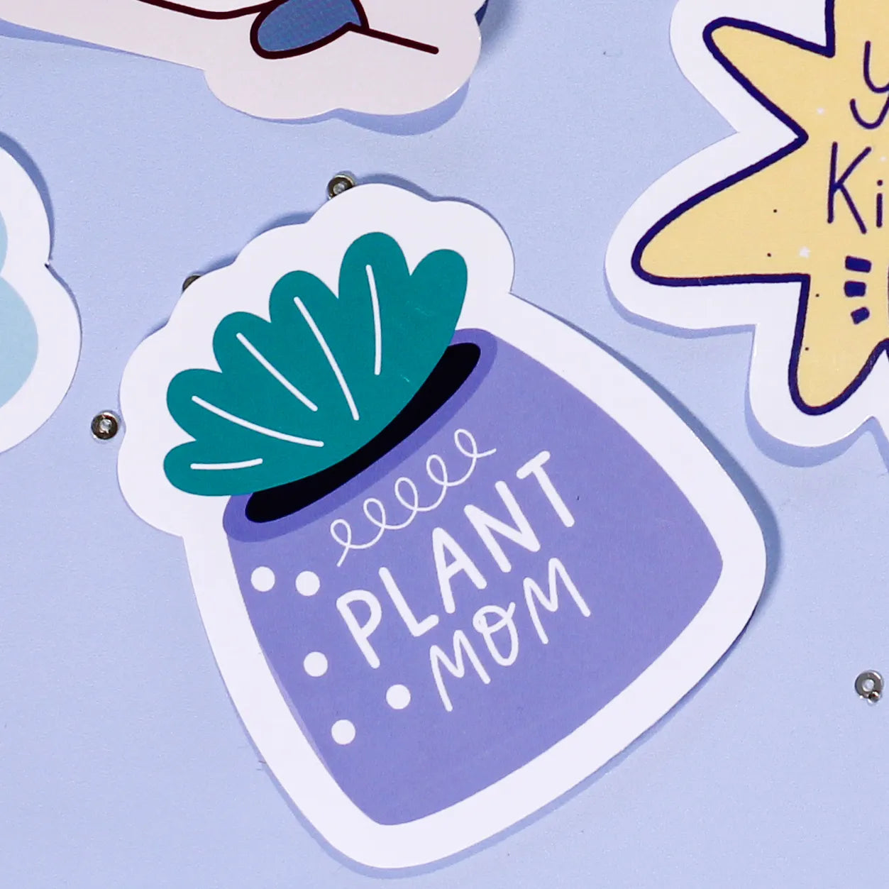 A close-up of our 'Plant Mom' sticker which is a purple pot with green leaves and text on a light blue background.