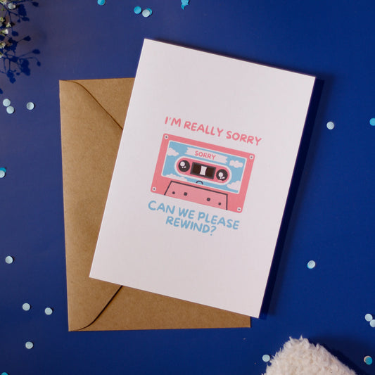 A white card with a cassette tape illustration accompanied by a brown envelope on a dark blue background with decorative elements.