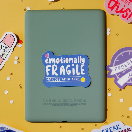 a 'emotionally fragile handle with care' sticker on a yellow background with confetti.