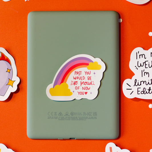 A rainbow sticker with 'Past You Would Be So Proud Of You' written on an orange background
