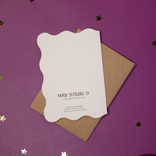 A white die-cut 'Welcome to the Universe Little One' greeting card back cover on a purple background with decorative elements.
