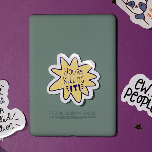 A yellow sticker in an organic shape with 'You're Killing It' on a purple background.
