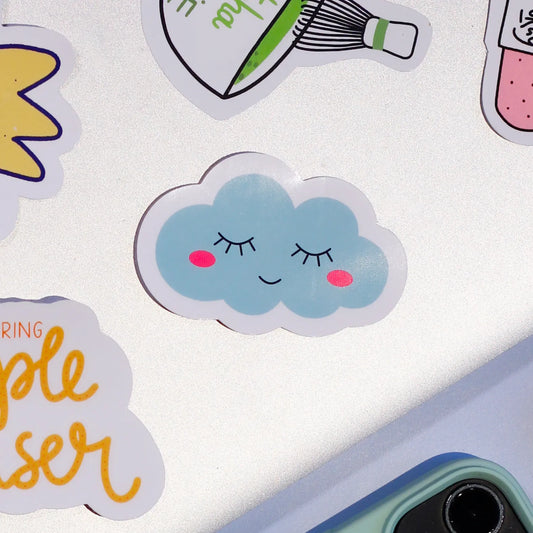 A close-up of our adorable 'Sleepy Cloud' sticker on a laptop on a light blue background.