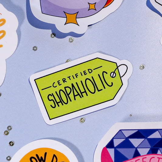 A close-up of our 'Certified Shopaholic' sticker on a colorful background