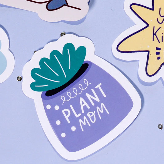 A close-up of our 'Plant Mom' sticker which is a purple pot with green leaves and text on a light blue background.